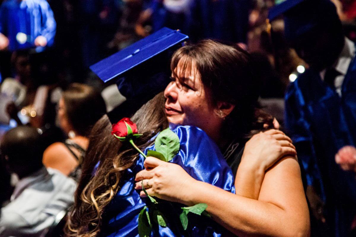 Edge High School graduate hugging person with rose