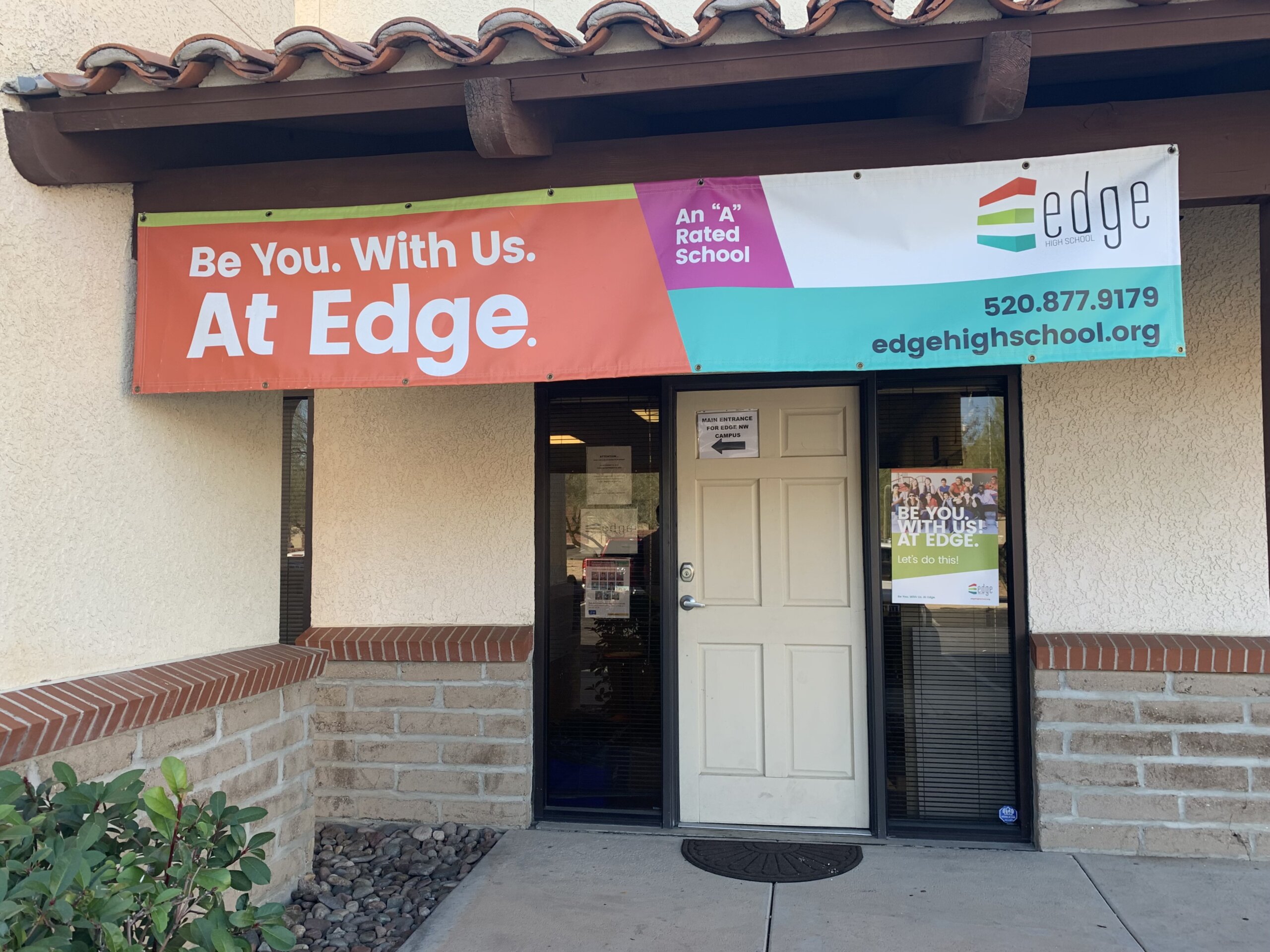 The front door of Edge High School with a banner that says Be You. With Us. At Edge.
