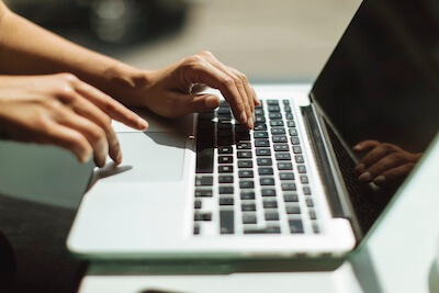 close up of someone's hands typing on a laptop
