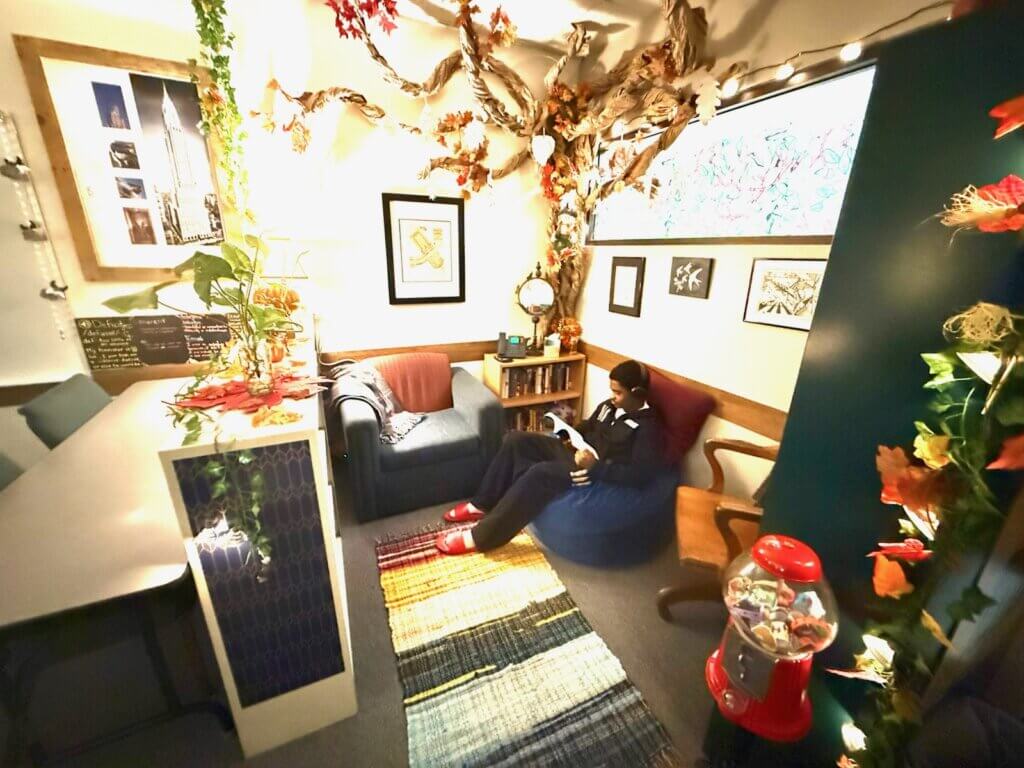 A student at Edge High School sits in a cozy reading space while reading a book. 
