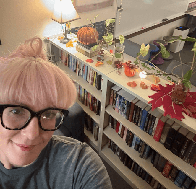 Ivy Knipe, teacher at Edge High School, takes a selfie in her classroom. The background is a warm, inviting reading space.