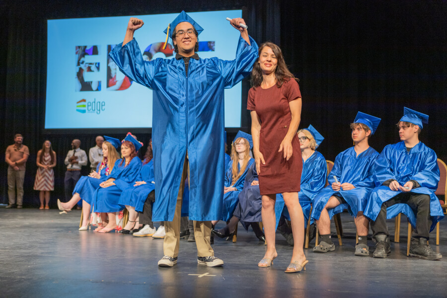 Edge High School Student proudly celebrates graduating while on stage with his peers.