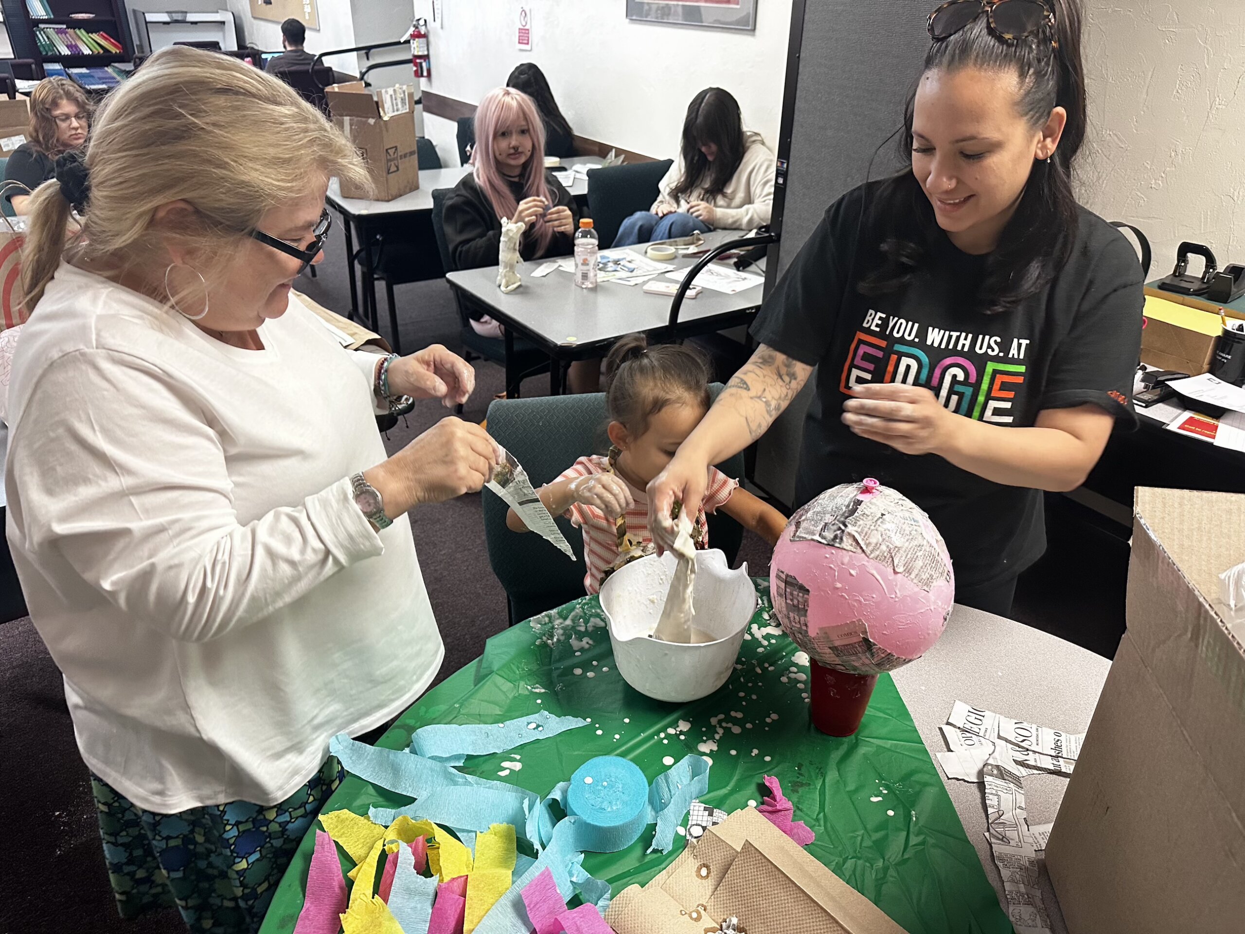 An Edge High School student works on an art project at a table with the art teacher.