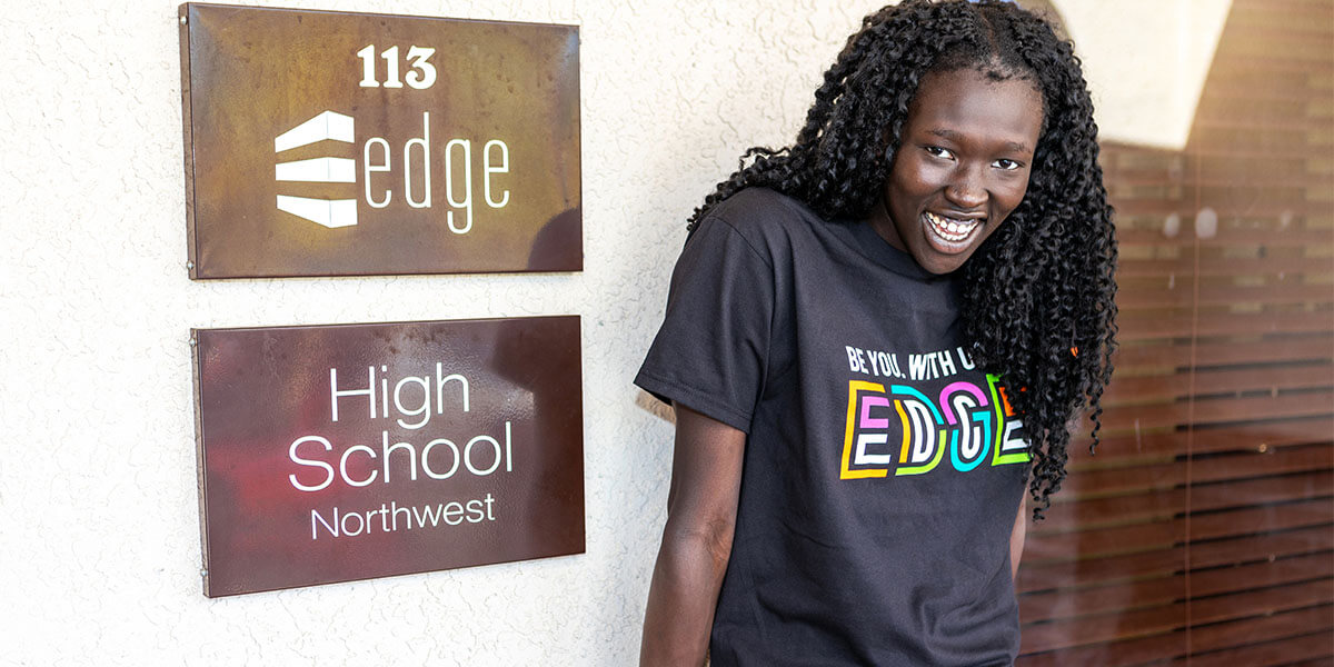 An Edge High School Northwest campus student stands outside wearing a Be You. With Us. At Edge t-shirt.